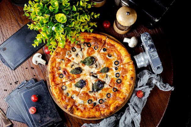 Pizza with mushrooms, olives and basil leaves