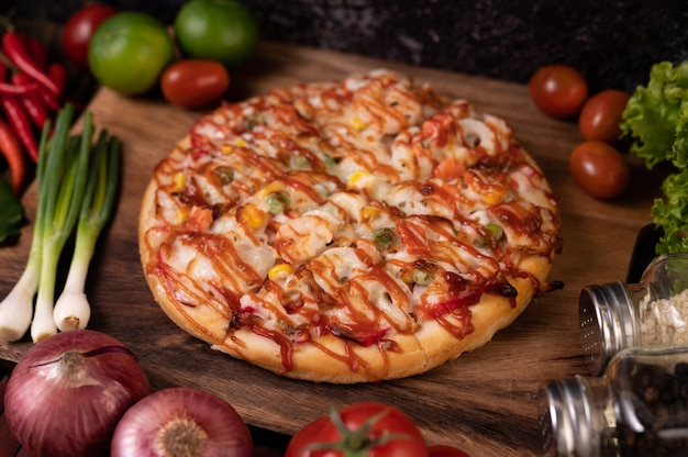 Pizza with sausage, corn, beans, shrimp and bacon on a wooden plate