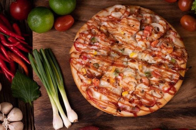 Free photo pizza with sausage, corn, beans, shrimp and bacon on a wooden plate