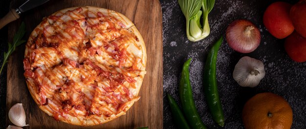 Free photo pizza with sausage, corn, beans, shrimp and bacon on a wooden plate