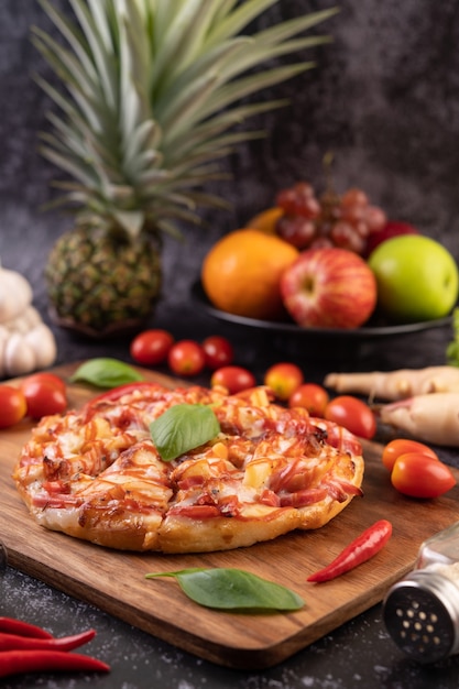 Free photo pizza in a wooden tray with tomatoes chili and basil.