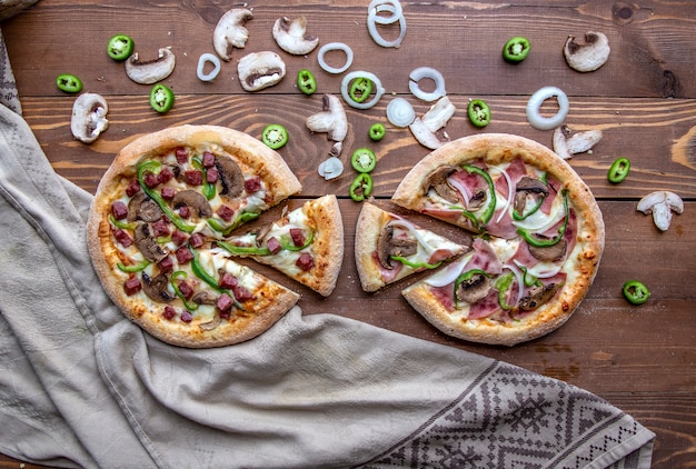 Pizzas with chopped sausages, meat, onions, mushrooms and green pepper