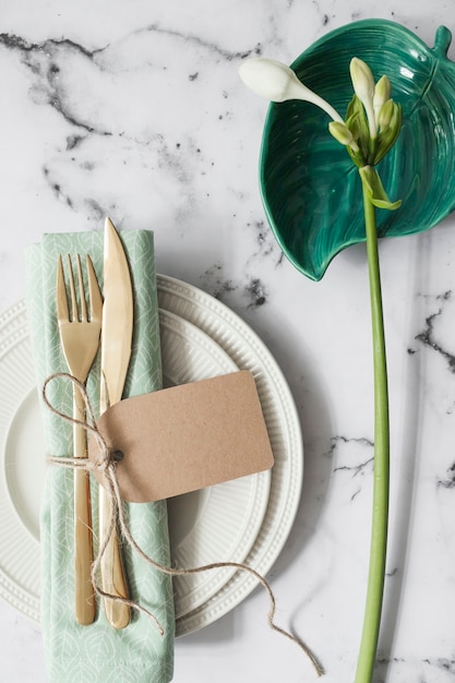 Place setting with white plates; folded napkin and cutlery with white flowers