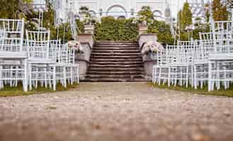 Free photo place for wedding ceremony with wedding arch decorated with flowers and white chairs on each side of archway outdoors. preparation for wedding ceremony outdoors near lake.