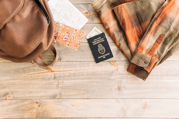 Free photo plaid shirt; bag; map; passport and currency on wooden backdrop