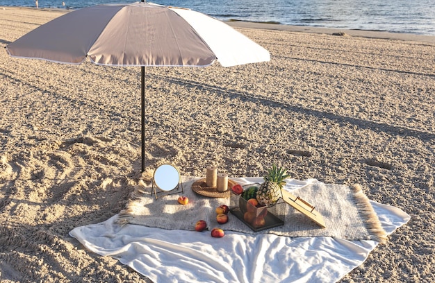 Plaid with fruits on the sandy seashore picnic by the sea