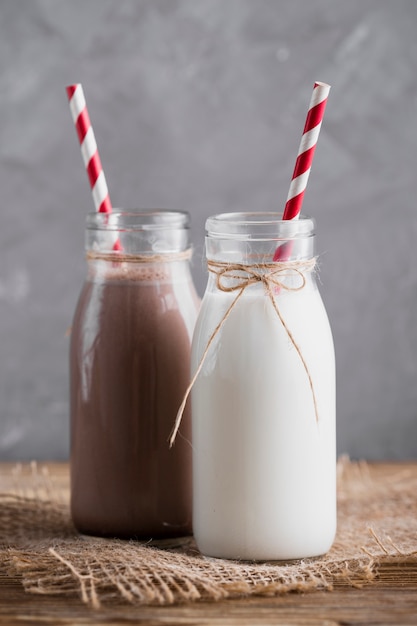 Plain milk and chocolate milk in bottles with straws