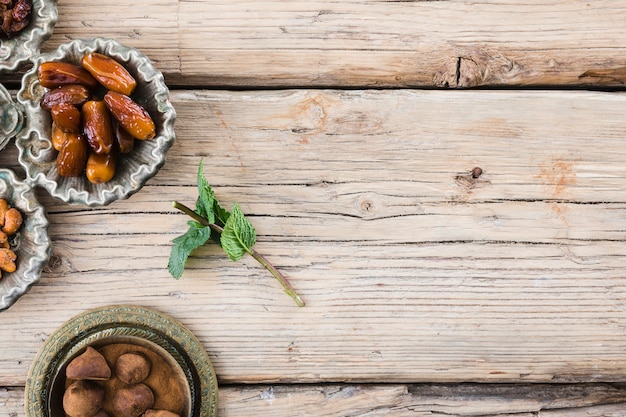 Plant twig near dried fruits and sweet on board