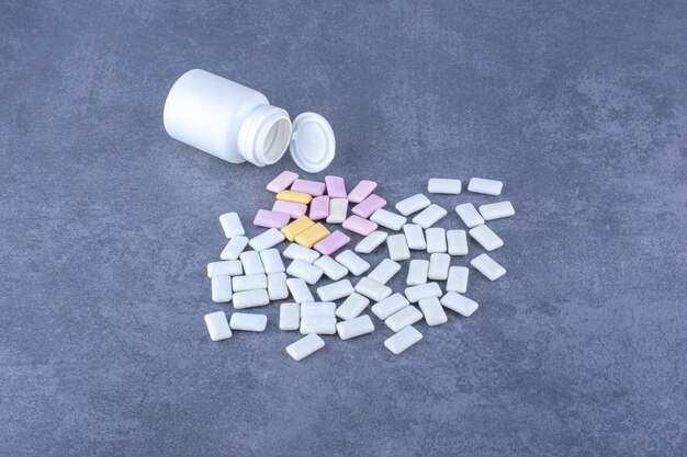 Plastic bottle fallen over next to a pile of gum on marble surface