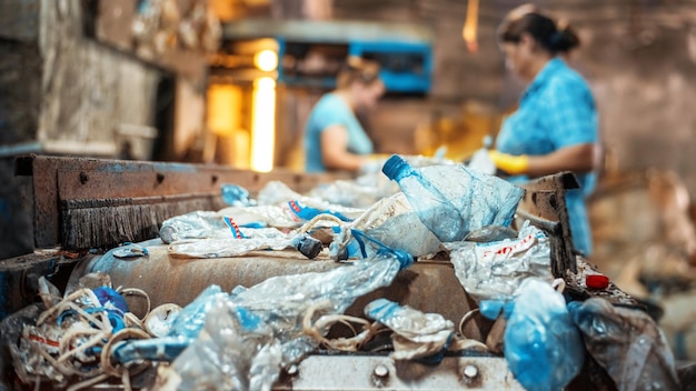 Free photo plastic garbage on a conveyor belt at waste recycling factory workers on the background