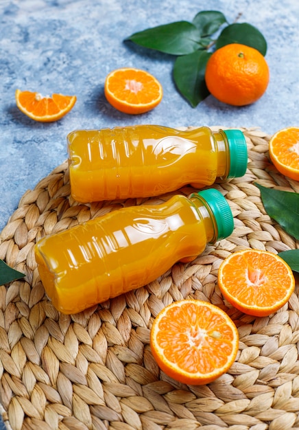 Free photo plastic mini bottles of organic fresh orange juice with raw oranges and tangerines