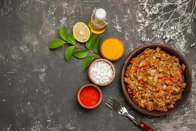 plate of beans and spices bowls of colorful spices lemon bottle of oil the plate of green beans on the dark table