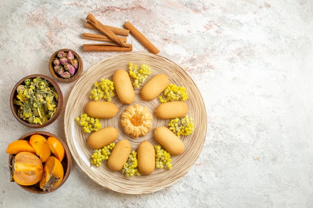 Free Photo a plate of cookie and cinnamon sticks and dry flowers and palm on left side of the ground