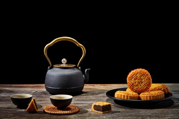 Plate of delicious cookies and a pot of tea on a wooden surface