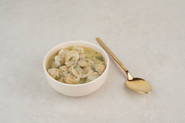 Free photo plate of dumplings with greens on white table.