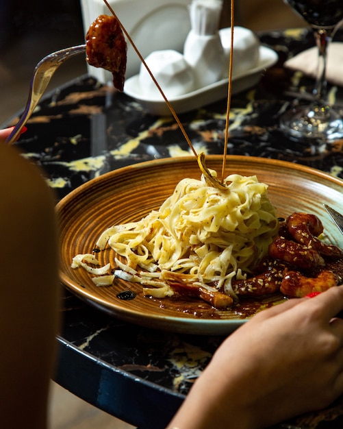 A plate of fettuccine with shrimp in teriyaki sauce