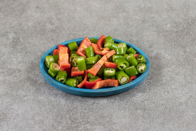 Plate of fresh salad with chili and bell peppers on marble surface. 