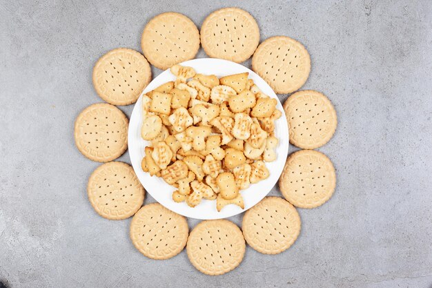 Plate full of cookie chips surrounded by biscuits on marble background. High quality photo