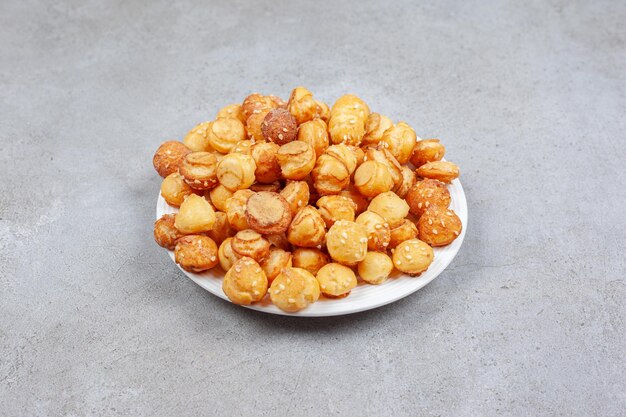 A plate full of small cookies on marble surface.