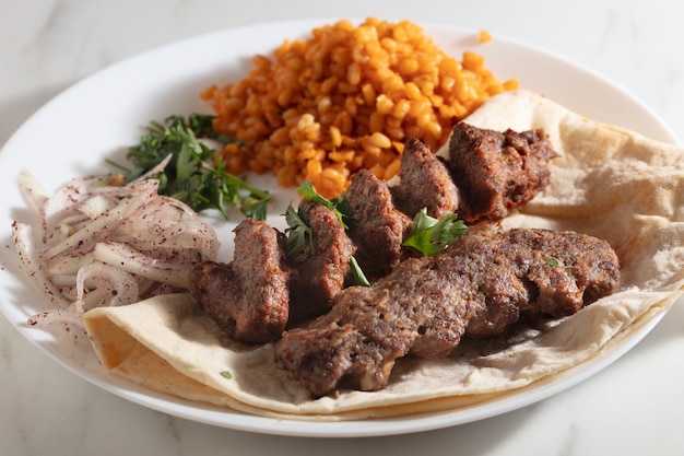 Plate of kebab with bread and onions and some spiced rice