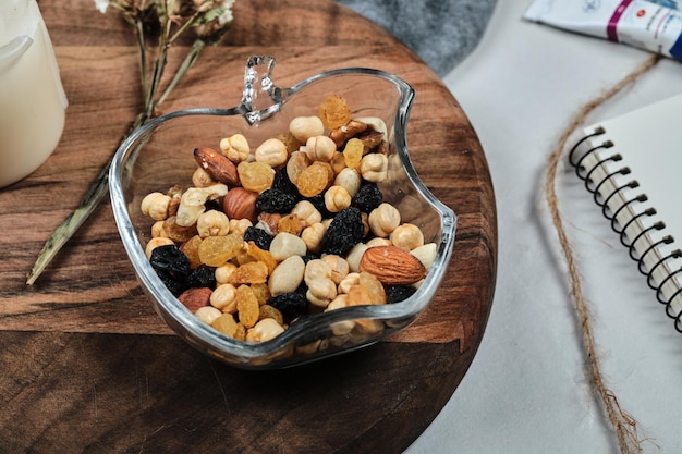 Free Photo a plate of nuts with candle, flower, paper and tubes on wooden board.