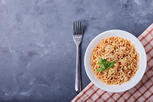 A plate of pasta in the middle on blue table .