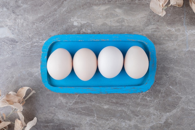 Free photo plate of raw eggs on marble background.