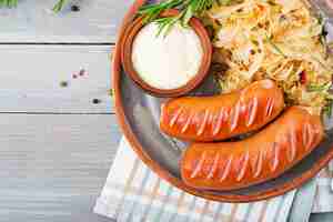 Free photo plate of sausages and sauerkraut on wooden table. traditional oktoberfest menu. flat lay. top view.