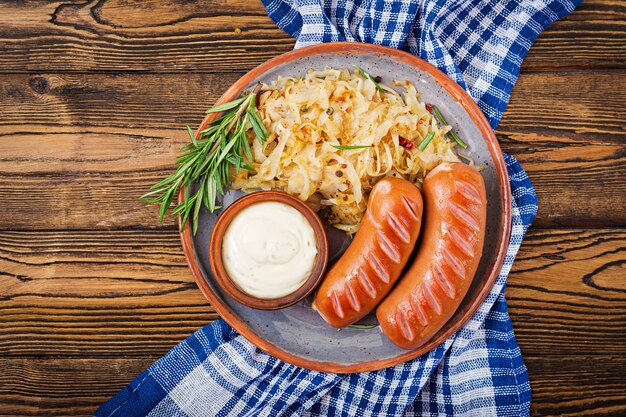 Plate of sausages and sauerkraut on wooden table. Traditional Oktoberfest menu. Flat lay. Top view.