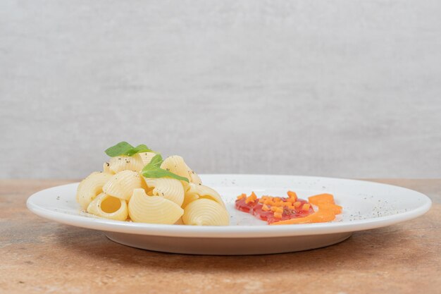 Plate of seashell shaped pasta with sauce on marble space. 