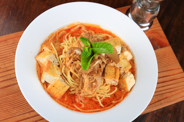 Plate of soup with spaghetti, bread pieces and decorated with greens