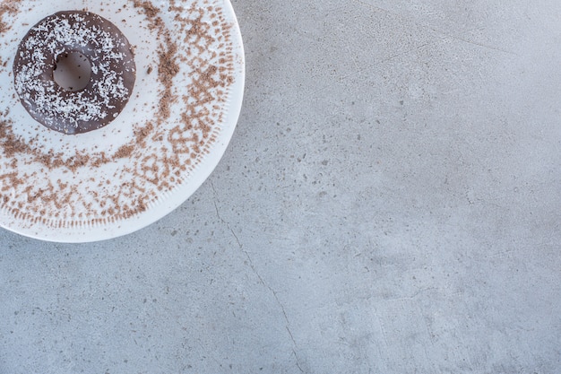 Plate of tasty single chocolate donut on stone table.