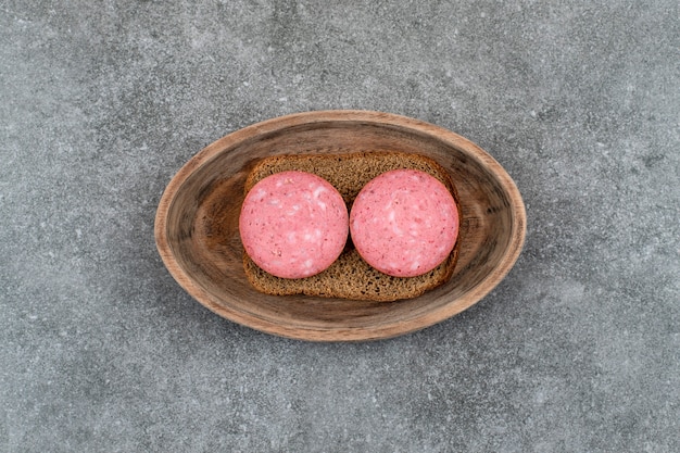 Free photo plate of toasts with salami placed on stone table.