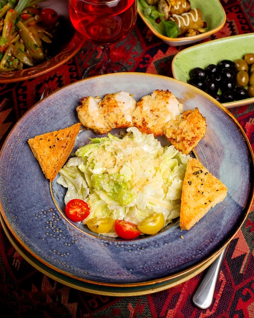 A plate of unmixed caesar salad with fried chicken pieces