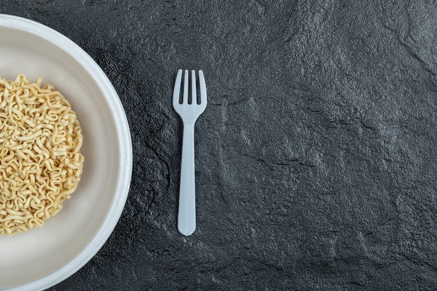 Free photo plate of unprepared noodles on a dark background.