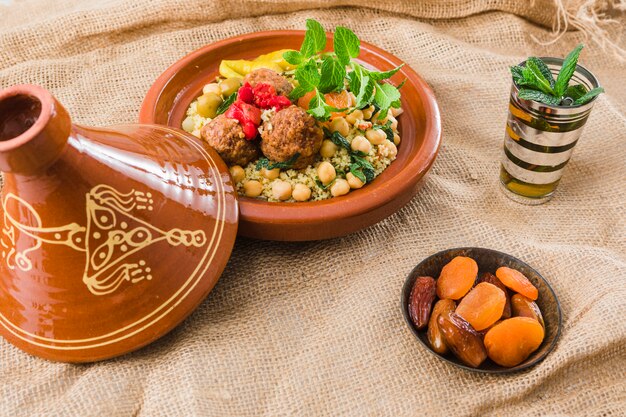 Plate with fresh food near cup and dried fruits on burlap