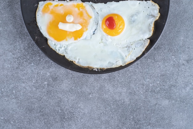 Free photo a plate with fried eggs on a gray surface