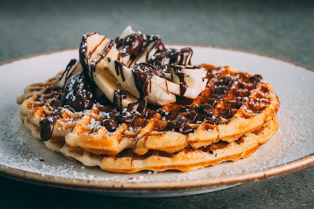 Plate with gourmet waffles with chocolate and banana slices