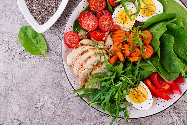 Free Photo plate with a keto diet food. cherry tomatoes, chicken breast, eggs, carrot, salad with arugula  and spinach. keto lunch. top view