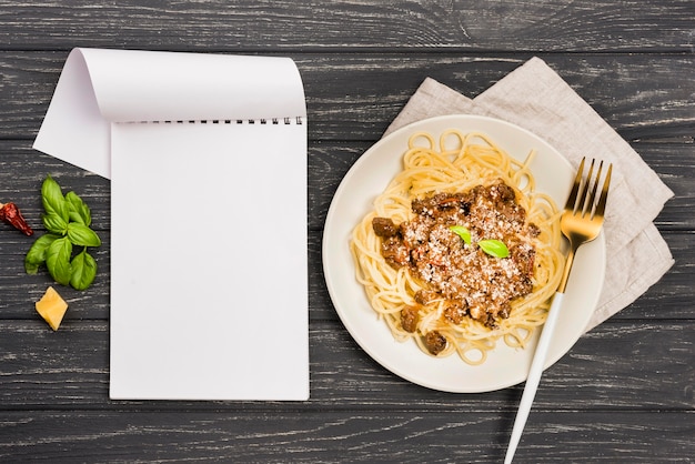 Free photo plate with spaghetii bolognese and notebook