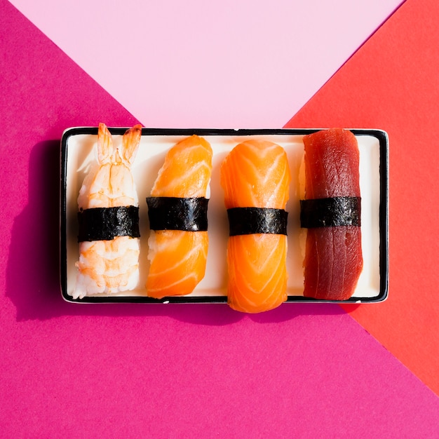 Plate with sushi on a rose and red background