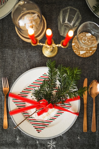 Free photo plate with twig and ribbon near flatware and candles