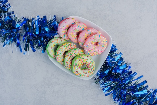 A platter of donuts on a garland on marble surface