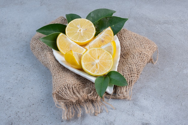 A platter of sliced lemons on a piece of cloth on marble background. 