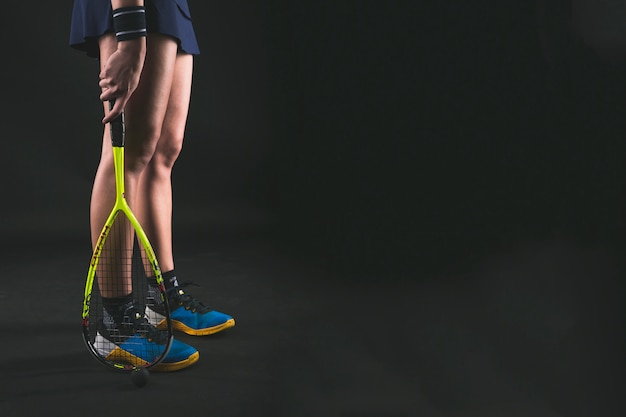 Player holding the racket next to her legs