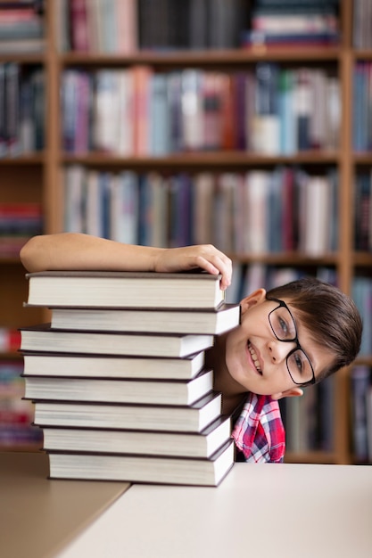 Free photo playful boy hiding behind stack of books