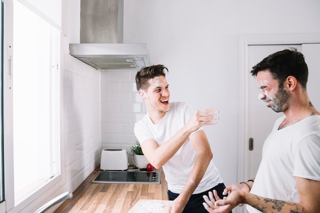 Playful gay couple having fun in kitchen