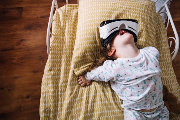 Free photo playful girl in vr goggles on bed