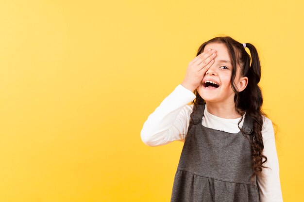 Playful little girl covering eye with hand