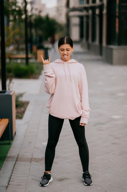 Playful portrait of pretty young woman having fun at the street